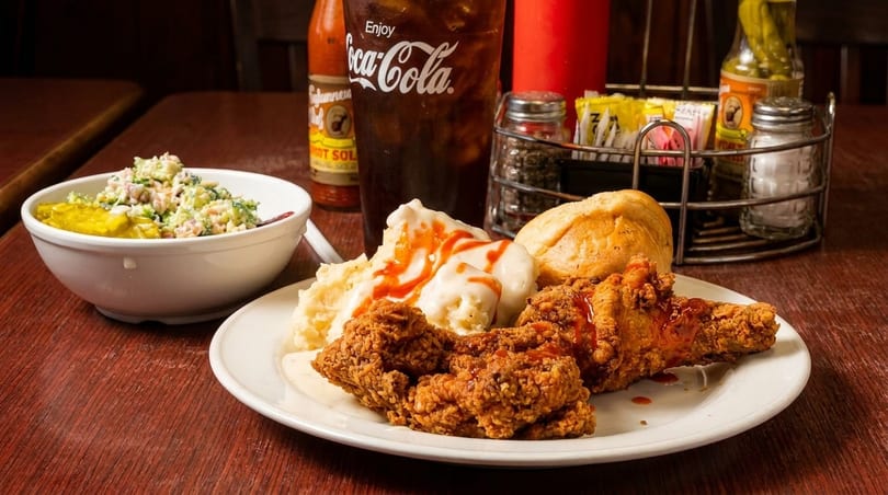 Fried chicken, mashed potatoes with gravy and hot sauce, a roll, and a side salad.