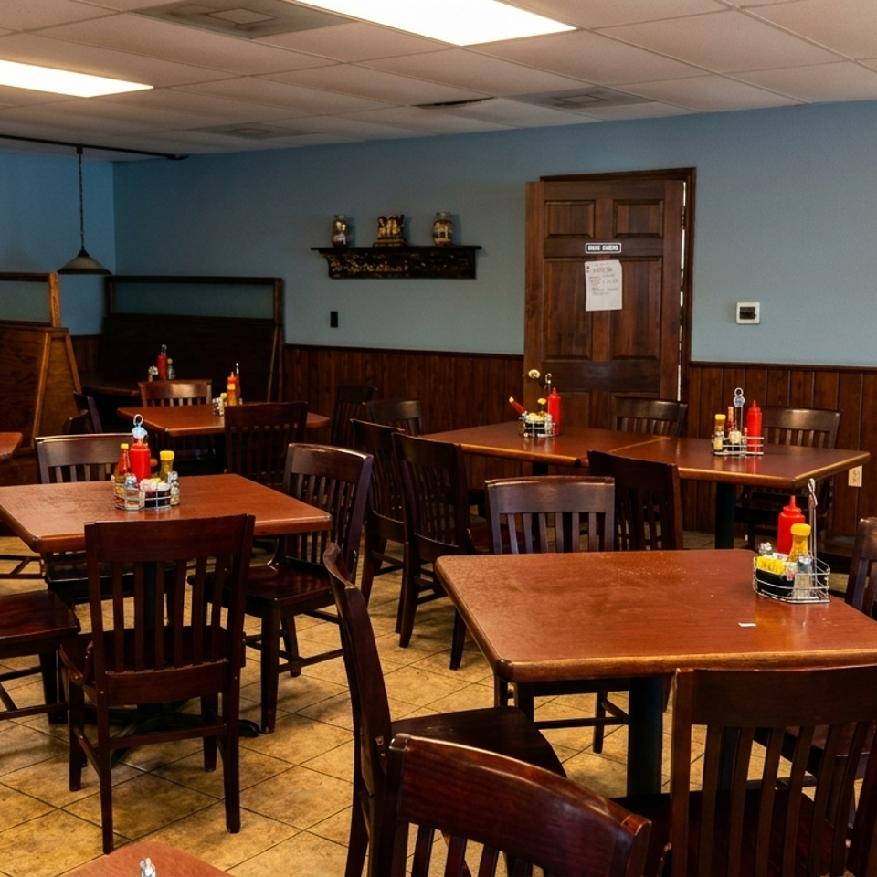 An empty diner interior with wooden tables, chairs, and booths, light blue walls, and tiled floors.